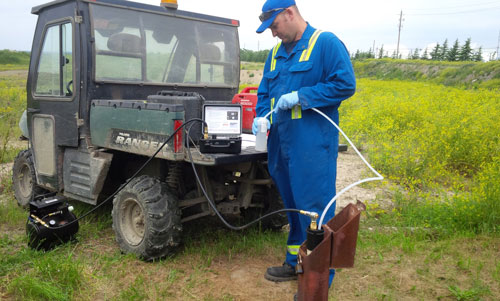 field technician taking groundwater sample using solinst electronic pump control unit