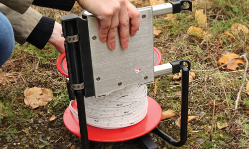 sliding power winder down the legs of a solinst water level meter reel to get it into the right position and align the rollers with the front and back faceplates
