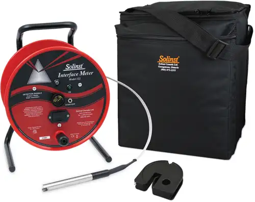 red solinst model 122 interface meter reel with a flat tape probe alongside a black padded carrying bag and a black plastic tape guide