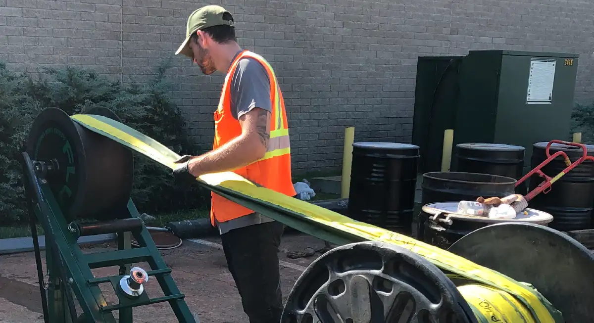 field operator setting up a flexible Solinst Flute blank liner spool onto a deployment stand at an environmental monitoring site
